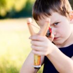 Little boy playing with slingshot