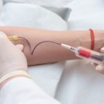 Doctor hands sticking needle into female vein for blood sampling