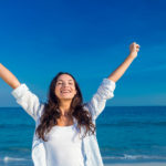 Happy woman smiling at the beach on a sunny day