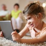 Granddaughter using tablet in living room.