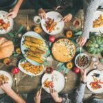 Friends eating at Thanksgiving Day table with vegetarian meals