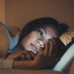Asian woman using mobile phone on bed
