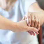 Elderly female hand holding hand of young caregiver at nursing home.Geriatric doctor or geriatrician concept. Doctor physician hand on happy elderly senior patient to comfort in hospital examination