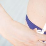 Slim attractive young lady wearing bikini in summer using fat caliper to measure bodyfat.