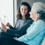 Smiling senior woman and her daughter using tablet computer