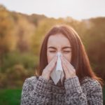 young woman with handkerchief. Sick girl has runny nose. Female model makes a cure for the common cold on an autumn background