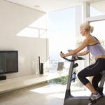 Mature woman on exercise bike watching television at home