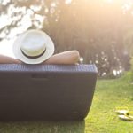 Woman in the hat sitting at the beach at sunset time