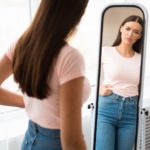 Sad Woman Measuring Waist After Weight Gain Standing At Home