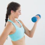 Side view of a smiling woman with dumbbell