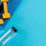 Dumbbells and bottle of water on blue background. Top view. Fitness, sport and healthy lifestyle concept