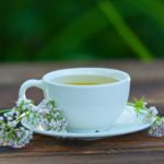 porcelainl cup with green tea on table