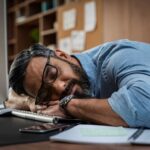 Tired businessman sleeping on computer desk