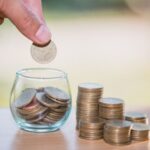 Woman hand putting coinIn the glass jar. Saving money wealth and financial concept.