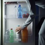 Woman taking a bottle of milk from the fridge late at night, lifestyle and diet concept