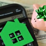 Piggy bank with calculator and paper house on dollar money background – Concept of saving money to buy a home and money bonus