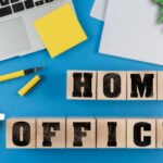 text HOME OFFICE on wood cubes besides laptop computer and notepad on desk