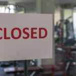 Closed sign on a glass of the door in gym due to Covid-19 or Corona virus outbreak pandemic crisis.