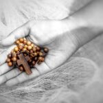 Wooden rosary with Jesus Christ holy cross crucifix in hand on black and white abstract art bakcground.