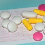 Medications in the form of tablets for oral administration against the background of an electrocardiogram. The heartbeat is shown on the graph, blue background