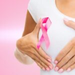 Woman with cancer awareness ribbon cupping her breast