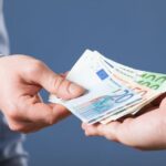 Businessman’s  hands exchanging euro on blue background