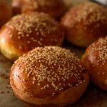 homemade burger rolls sprinkled with sesame seeds are baked in the oven